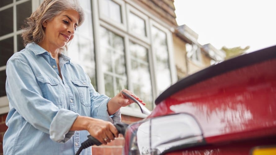 mujer que conecta su vehículo eléctrico a un cable de carga.