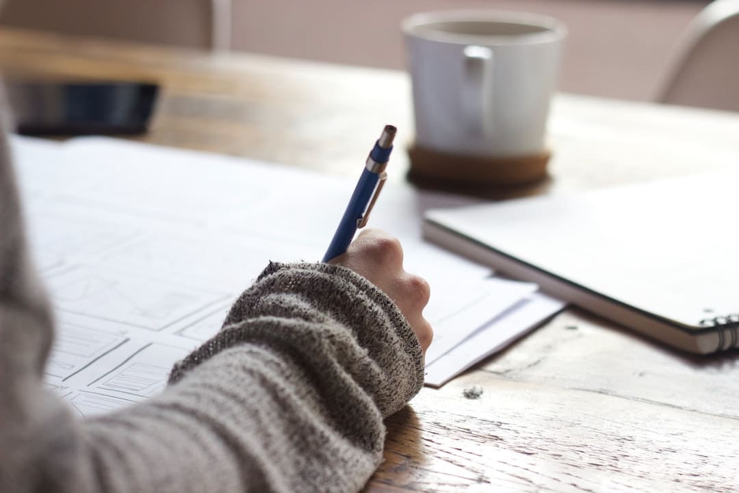 Persona escribiendo en una libreta con café.