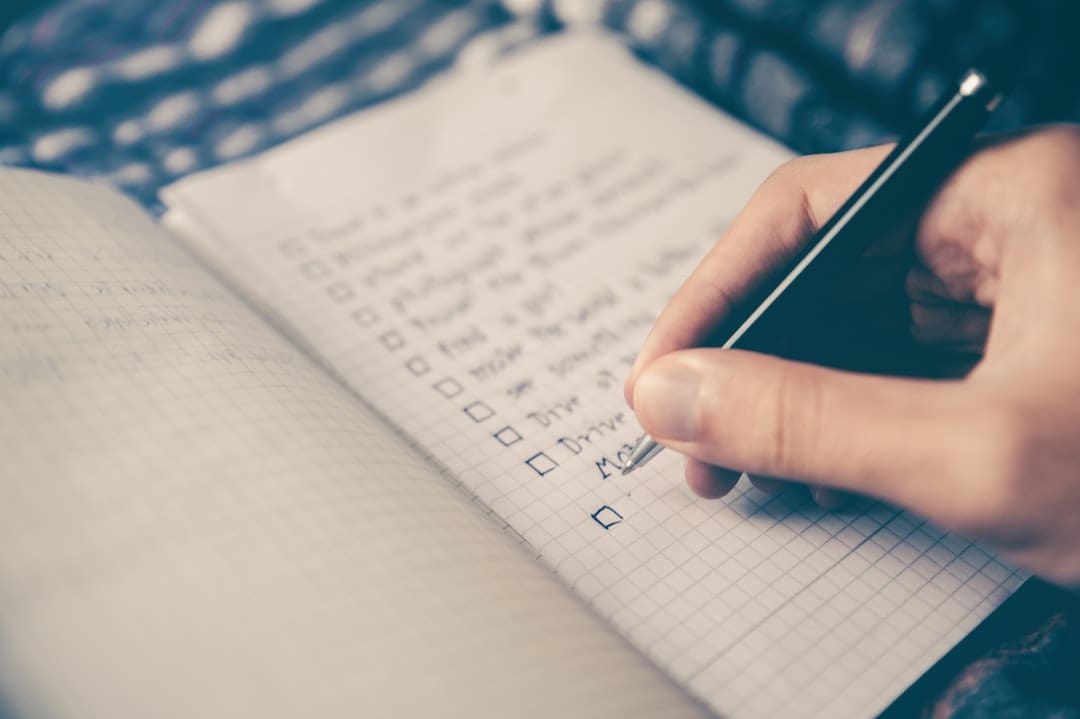 Persona escribiendo lista de tareas en cuaderno.