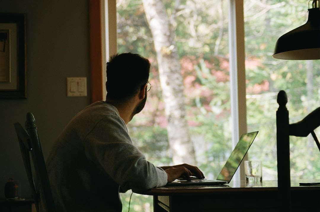 Hombre trabajando en computadora frente a ventana